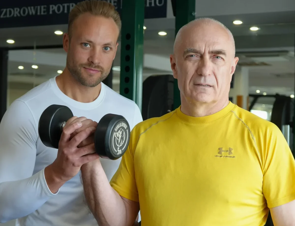 Trener pomaga podopiecznemu w ćwiczeniu z hantlem w Body Movement Mokotów
