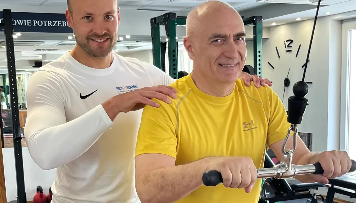 Trener pomaga podopiecznemu podczas ćwiczenia na wyciągu w Body Movement.