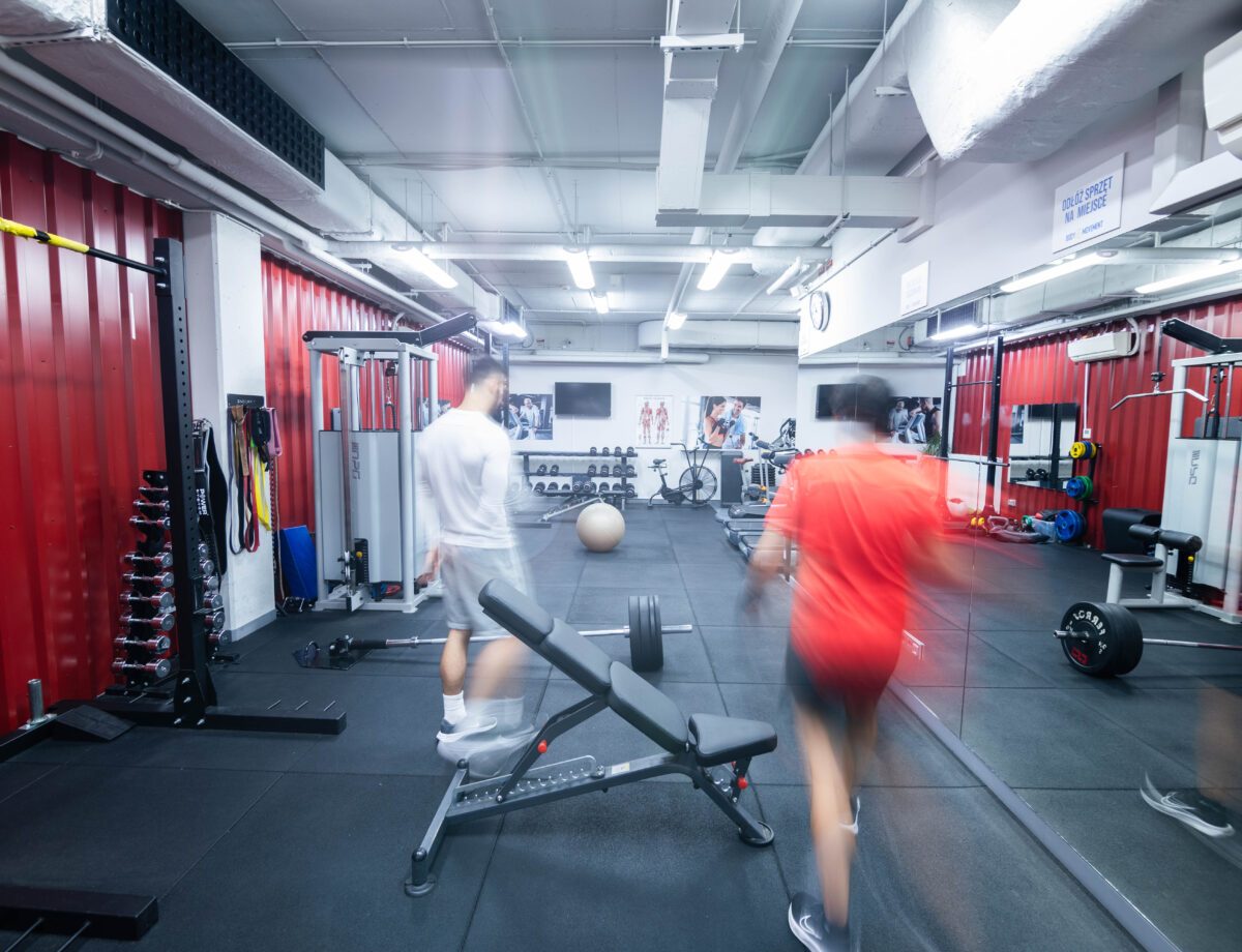 Sala treningowa z ławką, hantlami i wyciągami w Body Movement Mokotów