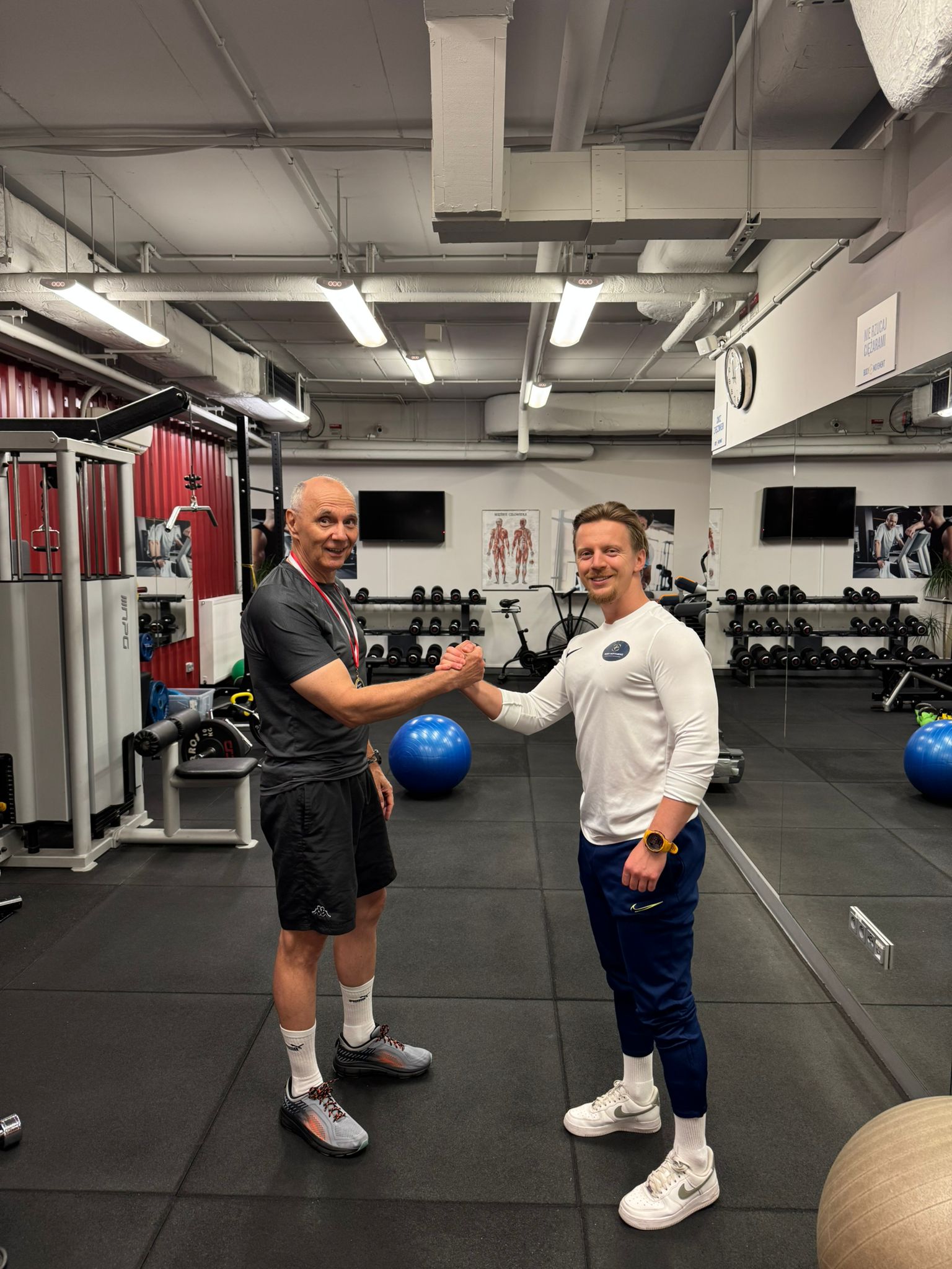 Podopieczny Body Movement z medalem za osiągnięcia sportowe obok trenera w studiu treningu personalnego w Warszawie na Mokotowie